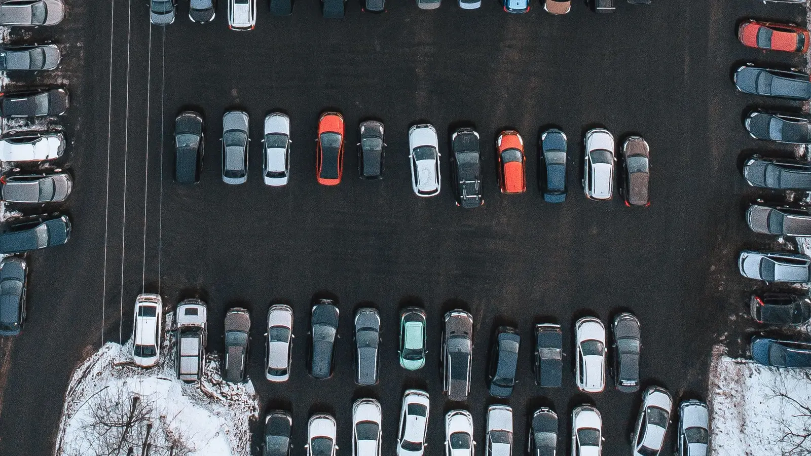 Aerial view of a parking lot full of cars after a light snow