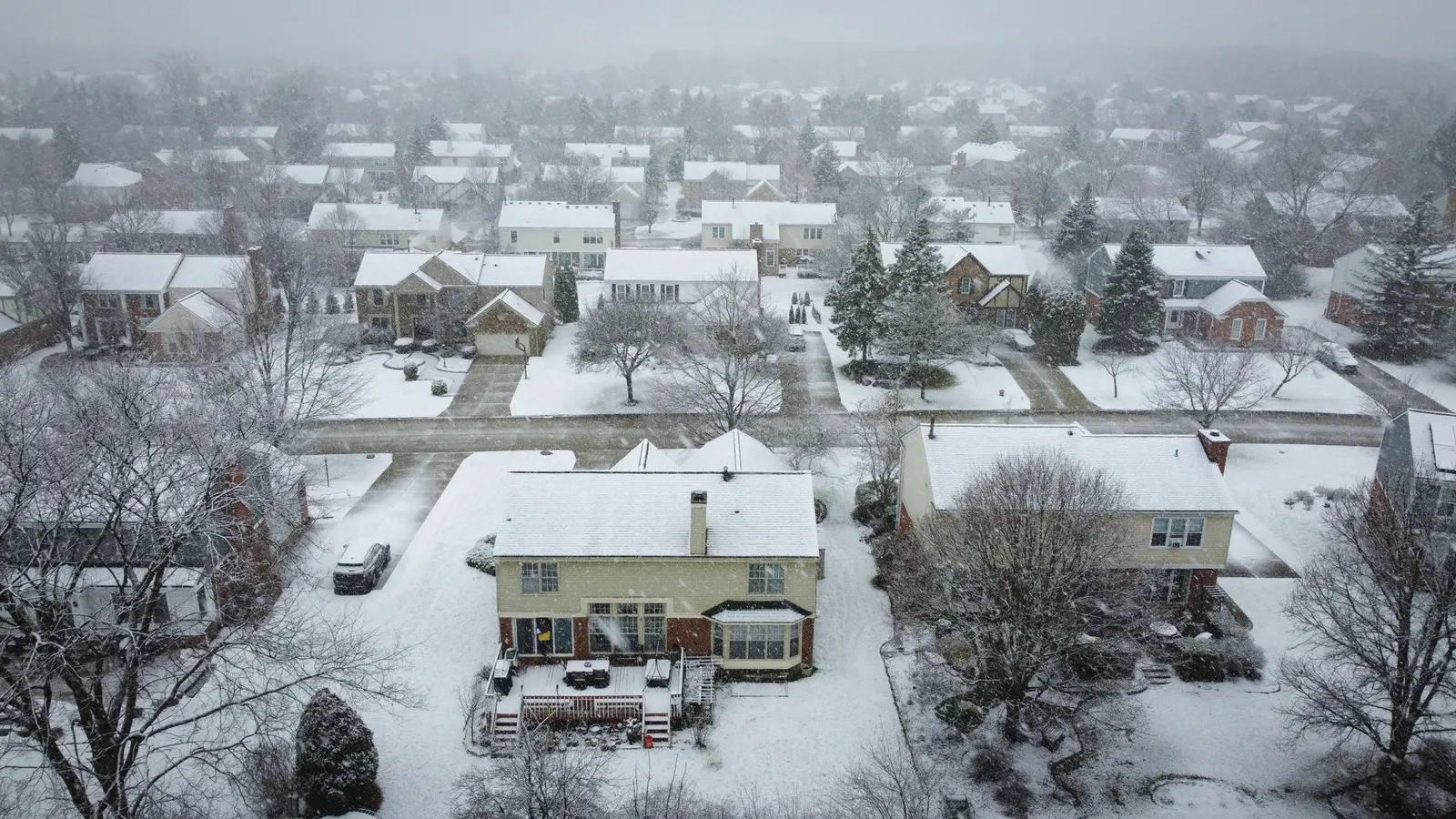 Aerial view of a snow-covered subdivision with cleared streets and driveways