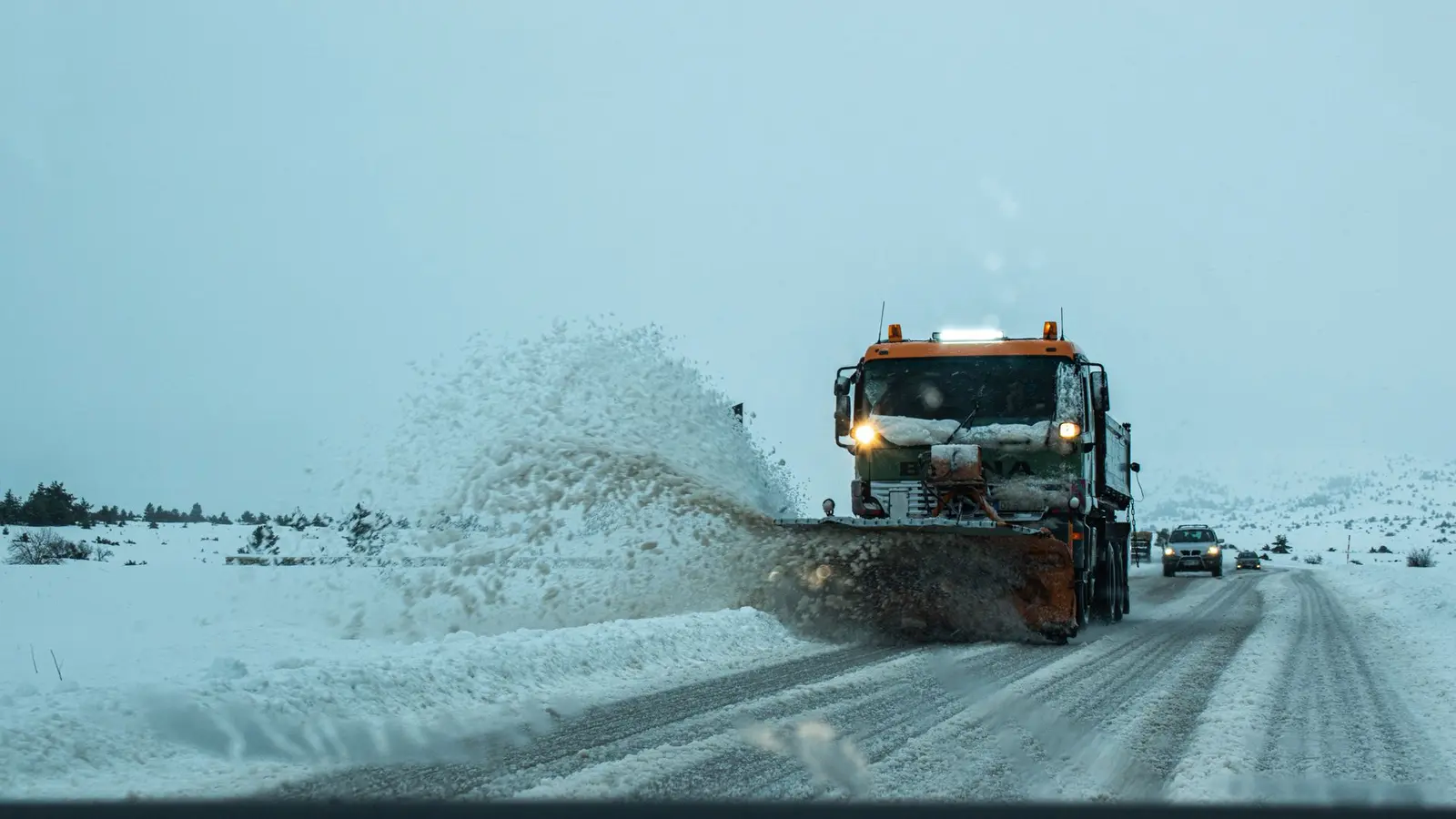 Plow truck throwing a spray of snow off a highway lane