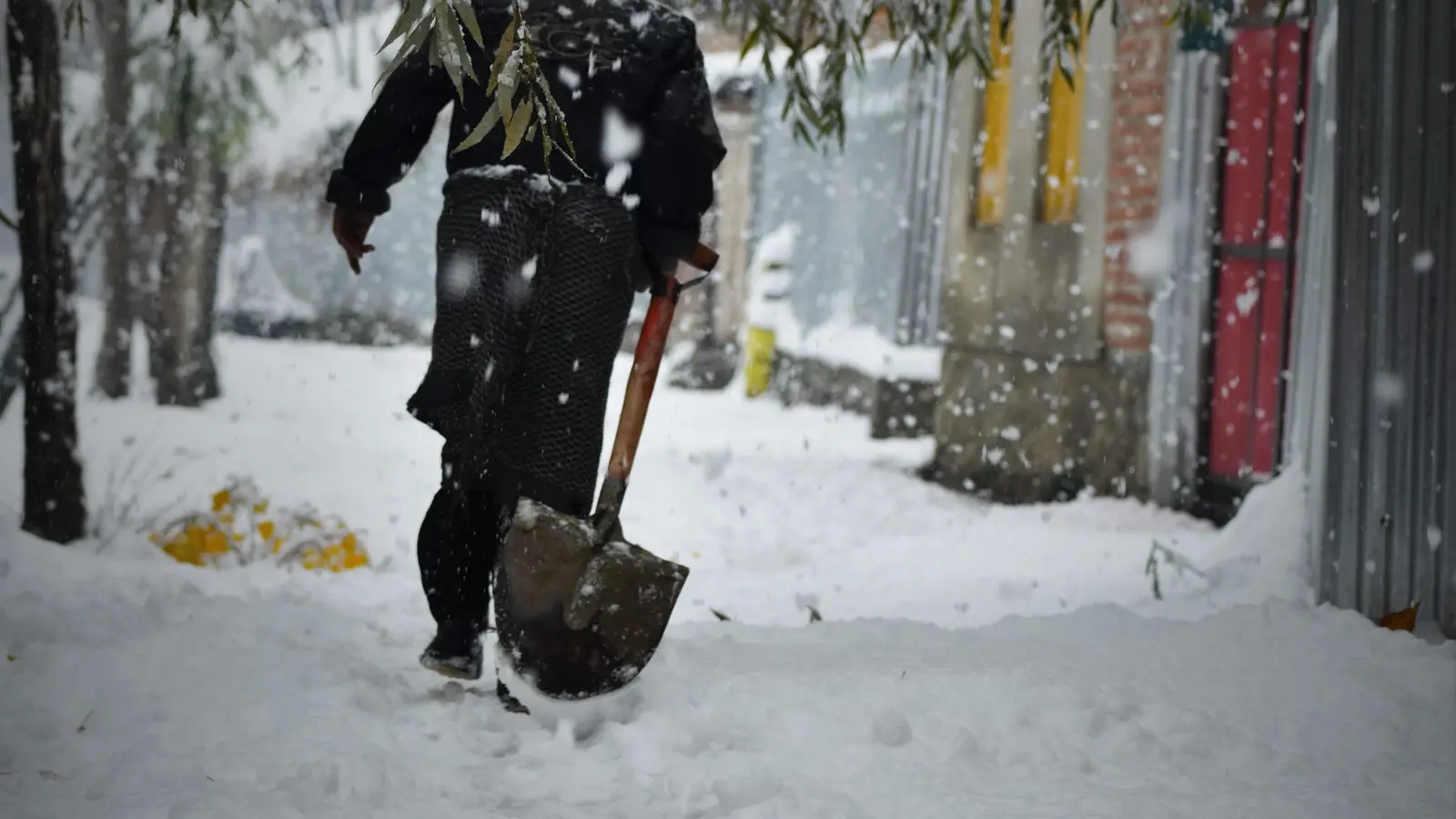 Person shoveling a snowy sidewalk outside a shop