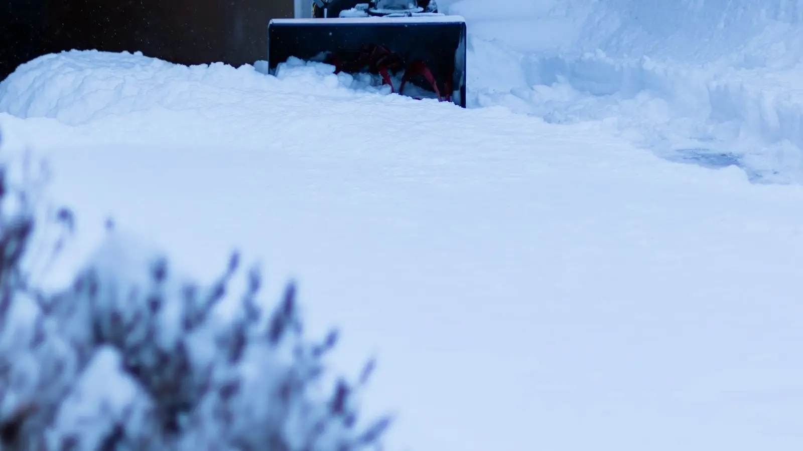 Person running a snowblower out of a garage after a storm
