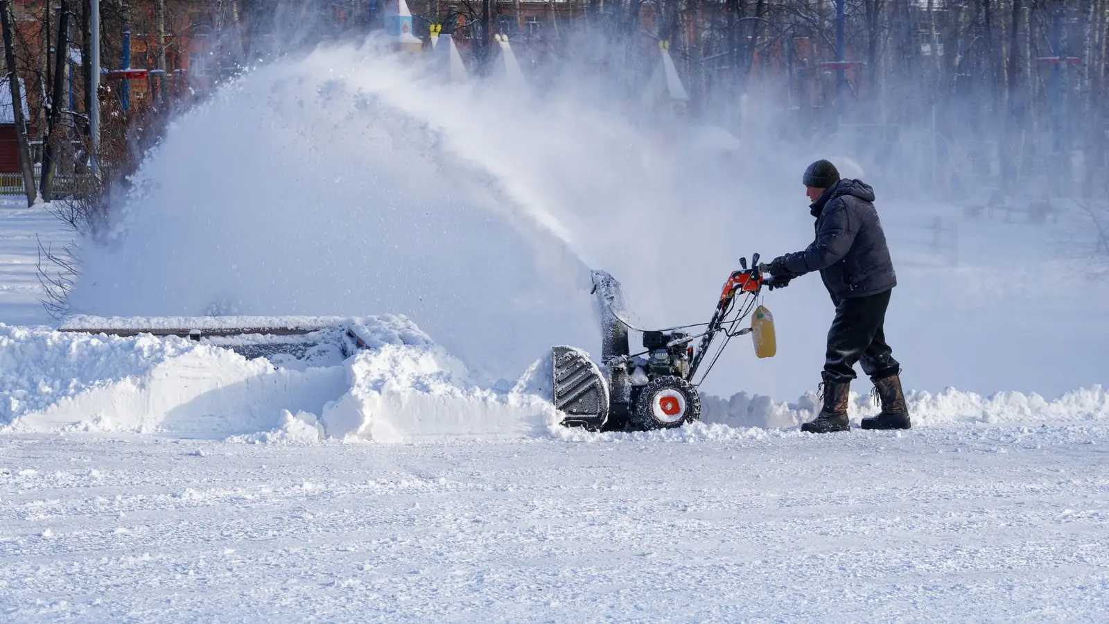 Person clearing deep snow with a snowblower throwing a high plume