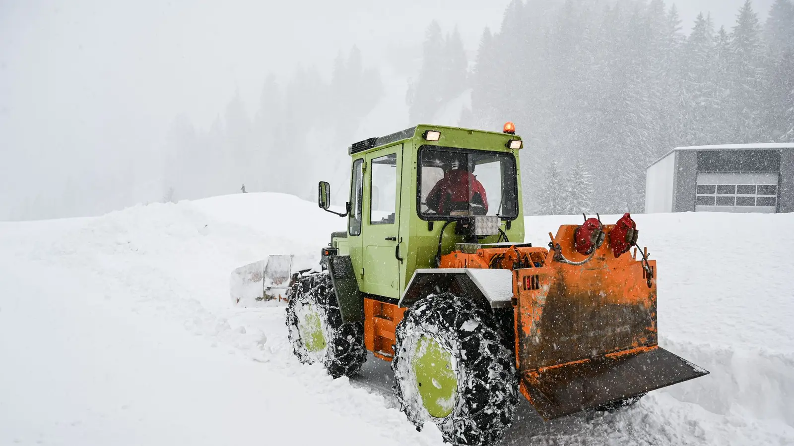 Tractor with a front plow pushing through deep snow
